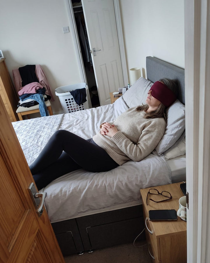 Frau ruht mit der Kühlmaske auf dem Bett
